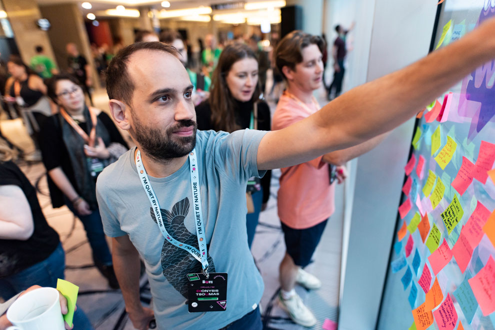 Conference attendee placing a sticky note on a window as part of a team building exercise