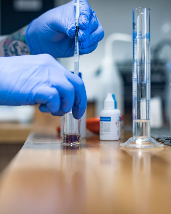 Lab technician adding liquid to a container from a pipette