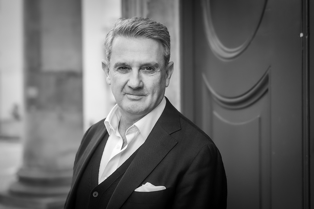 Corporate portrait of businessman in a blazer, black and white image with architectural backdrop
